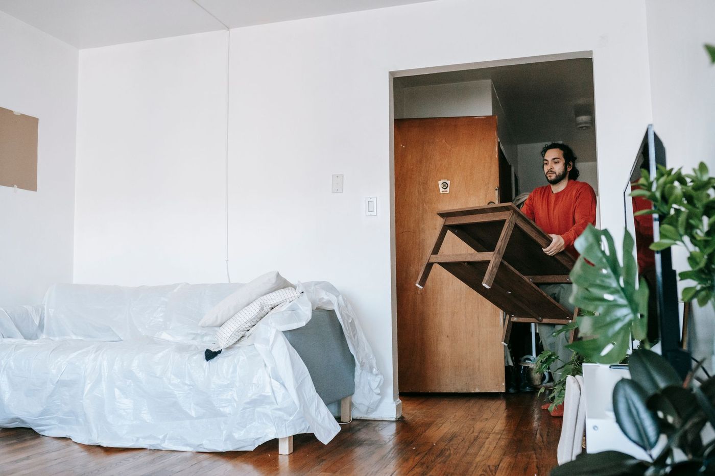 A crew member carrying a wooden table out of a flat during a clearance
