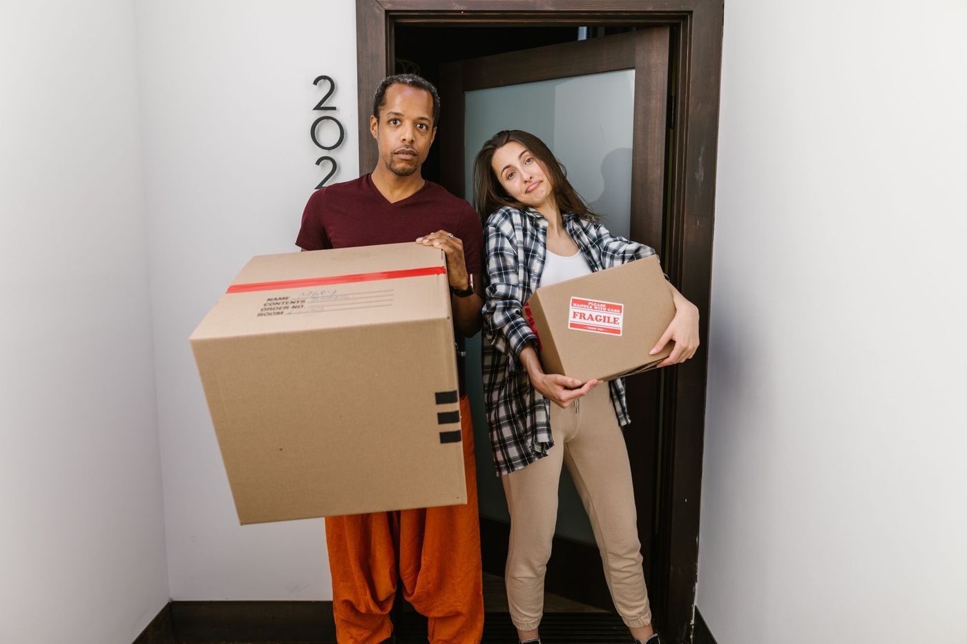 A couple standing in a doorway holding moving boxes