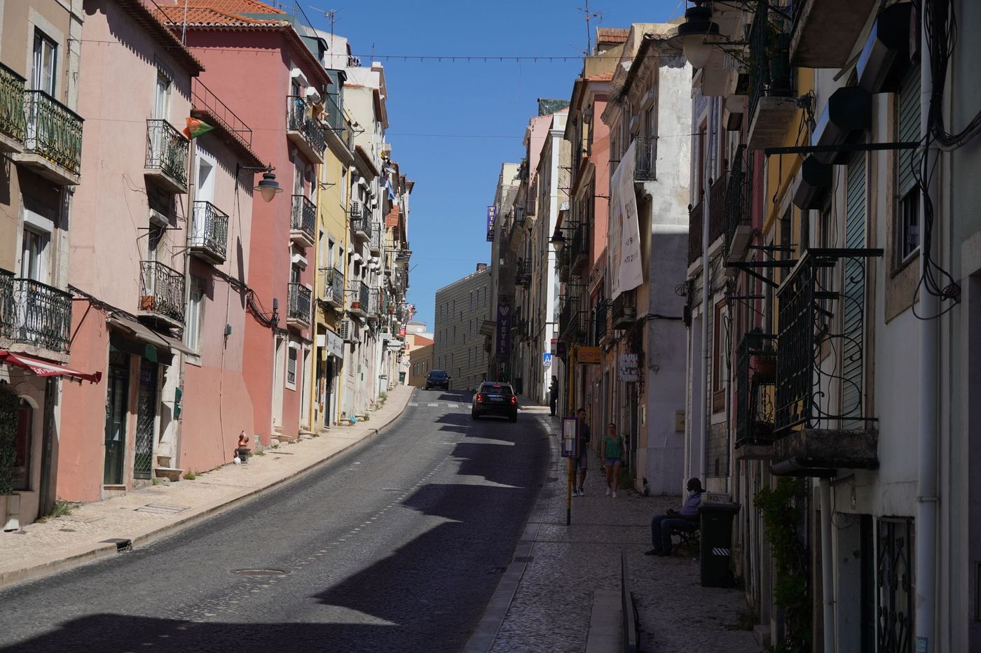 A sunlit hillside street of pastel townhouses in Lisbon
