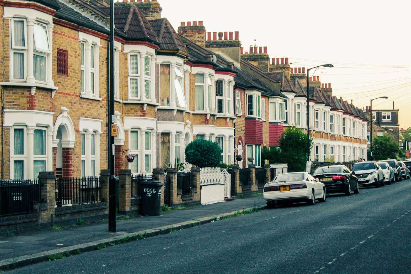 A street of Victorian terraced houses with bay windows and parked cars